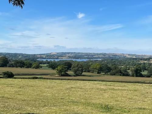 a field of grass with a lake in the distance at Beautiful home with stunning lake and valley views in East Harptree