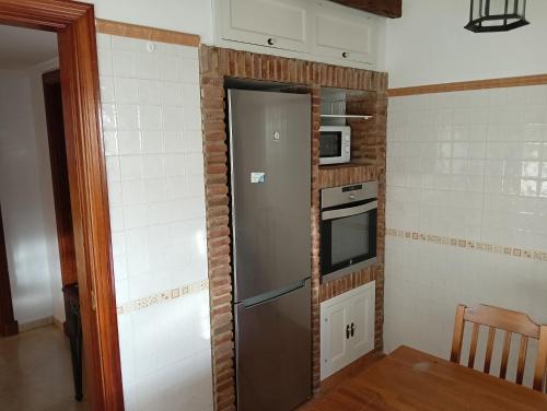 a small kitchen with a refrigerator and a microwave at Piso Centrico 1.5km Playa con gran terraza +vistas in Málaga