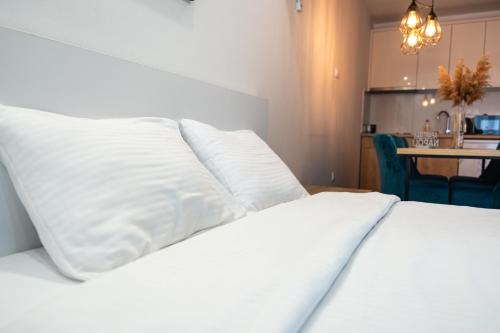 Una cama blanca con almohadas blancas encima. en Daisy resort en Novi Sad