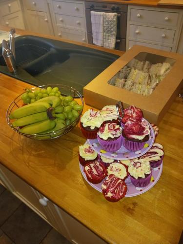 a counter with three plates of cupcakes and a bowl of bananas at Tullynacrunat Lodge in Castleblayney