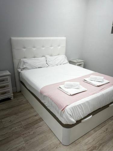 a white bed with two towels on top of it at Exyca Tetuán in Madrid