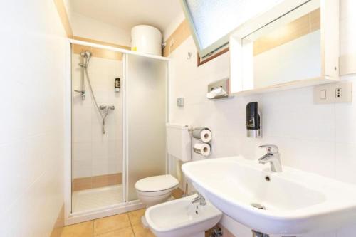 a bathroom with a sink and a toilet and a shower at Cozy and welcoming house with private garden in Lignano Sabbiadoro