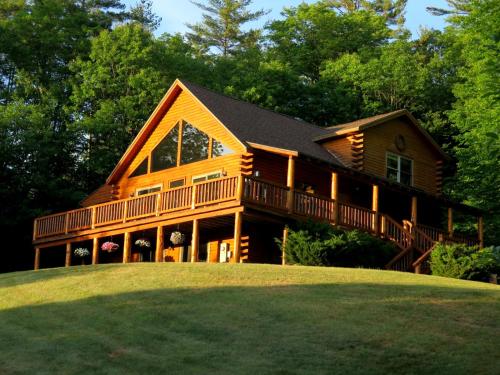 a large wooden house on a hill with trees at Mad River Cozy Cabin in Campton