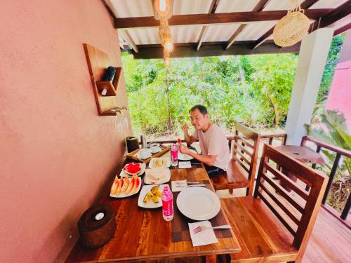 Un uomo seduto a un tavolo con del cibo sopra. di EdenHaven Cottage a Udawalawe