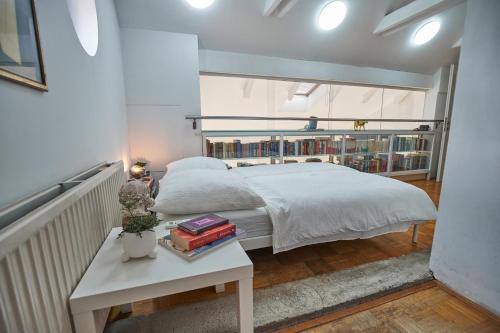 a bedroom with a bed and a table with books at Matic Spacious Modern Apartment in Ljubljana