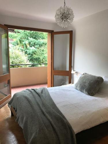 une chambre avec un lit et une grande fenêtre dans l'établissement Modern and stylish 3-bedroom apartment with views - centre of St Gervais, à Saint-Gervais-les-Bains