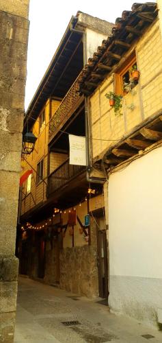 an old building with a balcony on a street at Hotel Judería Valle del Jerte in Cabezuela del Valle