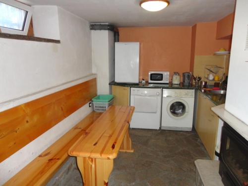 a small kitchen with a wooden bench and a washing machine at Guest House The House in Veliko Tŭrnovo