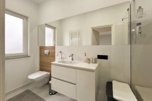 a white bathroom with a sink and a toilet at Apartament la munte in Borşa