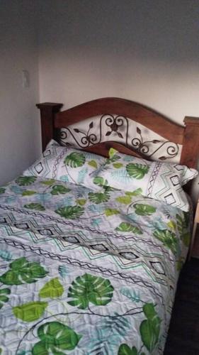 uma cama com um edredão verde e branco em Hotel Mamma Mia em Duitama