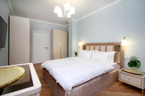 a bedroom with a large white bed and a table at Modern, Spacious and Elegant Apt in Almaty