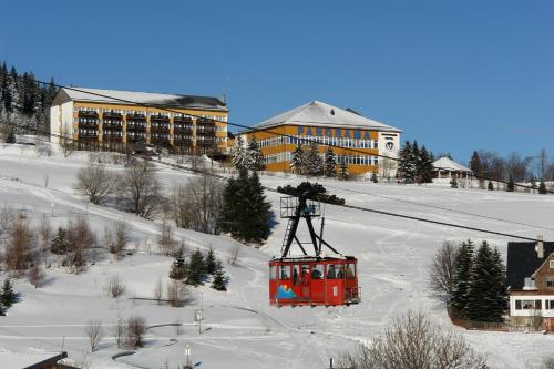 a red ski lift with people on it in the snow at Panorama Hotel Oberwiesenthal in Kurort Oberwiesenthal