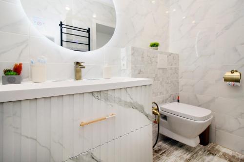 a bathroom with a toilet and a sink and a mirror at Modern, Spacious and Elegant Apt in Almaty