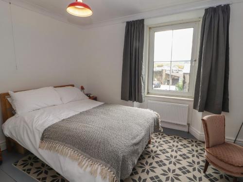 a bedroom with a bed and a window and a chair at Badgers in Sedbergh