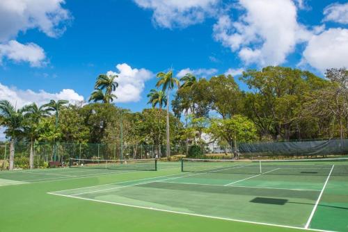 a tennis court with palm trees in the background at Condos at Glitter Bay Estate by Blue Sky Luxury in Saint James