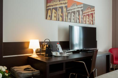 a desk with a television and a lamp on it at Euro Hotel Residence in Concorezzo