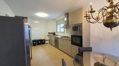 a kitchen with a table and a chandelier at Opening Doors Premiá Dalt Amazing views w pool in Premia de Dalt
