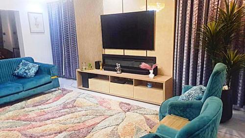 a living room with two blue chairs and a television at Luxury 4 Bdr Home in the city in Abuja