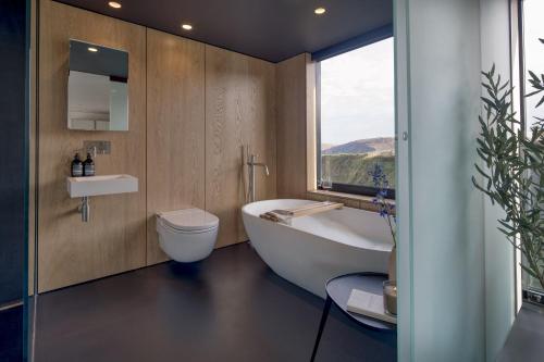 a bathroom with a tub and a toilet and a window at Edge House in Aberporth