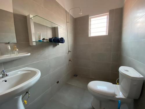 ein Badezimmer mit einem weißen WC und einem Waschbecken in der Unterkunft Les Amazones Rouges Chambre Jaune in Ouidah