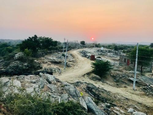 a dirt road on a hill with the sunset in the background at Deogarh Hills A Village Experience Property in Kaunthal