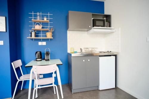 una cucina con pareti blu e tavolo e sedie di La Company Des Concierges : La Bonbonnière a Caen
