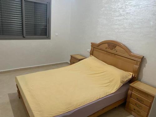 1 cama con cabecero de madera en un dormitorio en Résidence HAMZA en Douar Ourlali