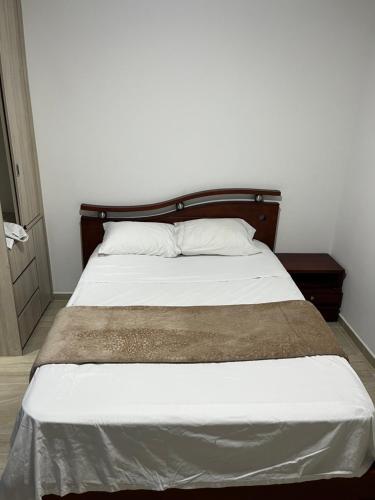 uma cama com uma cabeceira em madeira e lençóis e almofadas brancos em Apartaestudio en la mesa em La Mesa