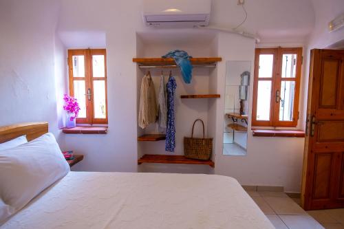 1 dormitorio con cama blanca y ventanas en Bougainville House, en Megalokori
