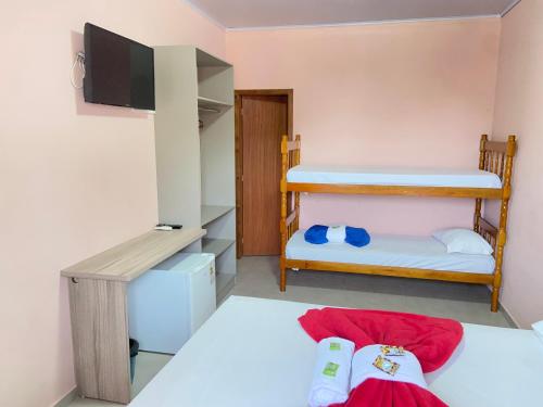 a room with two bunk beds and a flat screen tv at Pousada Villa Sambaqui in Penha