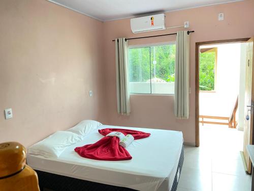 a room with a bed with a red robe on it at Pousada Villa Sambaqui in Penha