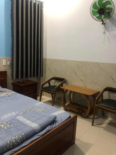 a bedroom with a bed and two chairs and a table at Nhà Nghỉ A&Em in Xã Bình Hòa