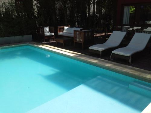 a swimming pool with two chairs and a bed at Posta Cangrejo Apart in Las Gaviotas