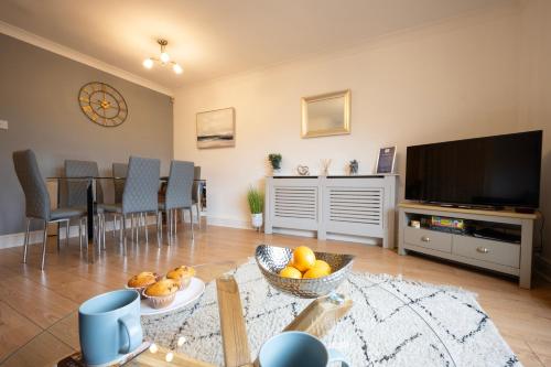 a living room with a television and a table with chairs at The Marlowe - Beautiful house in the heart of Canterbury with Free Parking in Canterbury