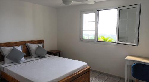 een slaapkamer met een bed en een raam bij VACANCES OUEST REUNION in La Possession