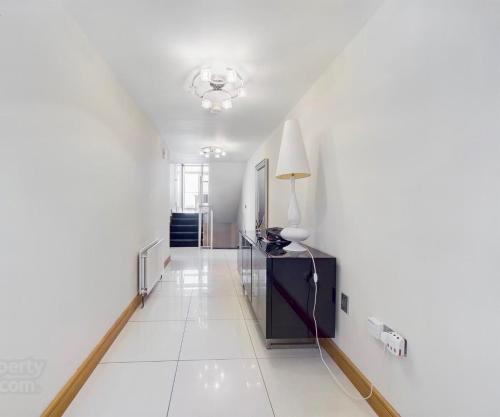 a hallway with white walls and a lamp on a table at Atlantic View Coach House - tourist board approved in Portstewart
