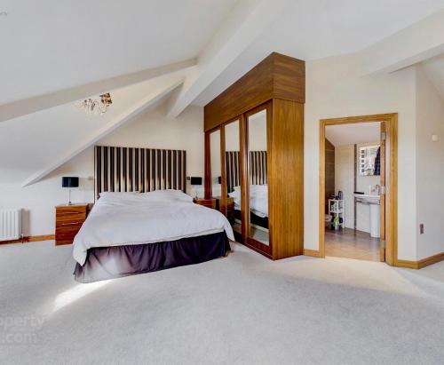 a bedroom with a large bed and a mirror at Atlantic View Coach House - tourist board approved in Portstewart