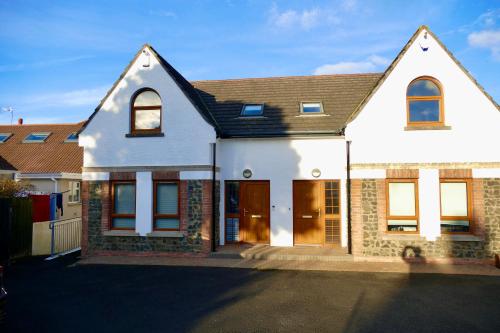 a white house with a brown roof at Atlantic View Coach House - tourist board approved in Portstewart