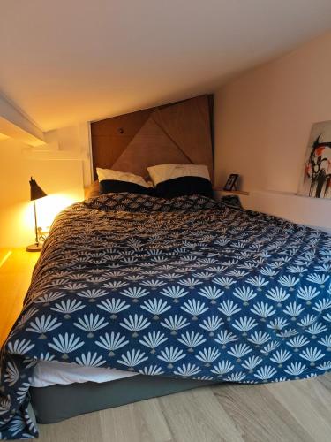 - une chambre dotée d'un grand lit avec un couvre-lit bleu et blanc dans l'établissement Appart calme Montmartre, à Paris