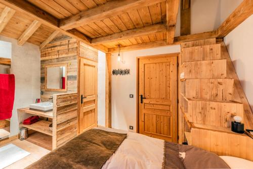 a bedroom with a bed and a wooden wall at Chalet savoyard d'exception avec piscine chauffée in Bourg-Saint-Maurice