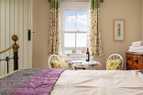 a bedroom with a bed and a table and a window at Portloe Cottage Padstow in Padstow