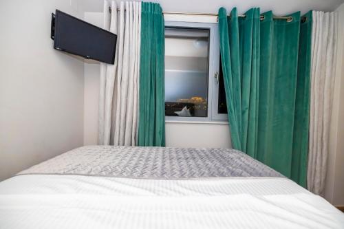 a bedroom with a bed with green curtains and a window at PANORAMIC SUITE in Athens