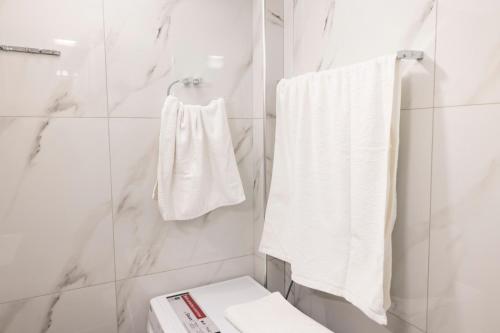 a white bathroom with white towels hanging on a wall at PANORAMIC SUITE in Athens