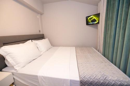 a bedroom with a white bed with a tv on the wall at PANORAMIC SUITE in Athens