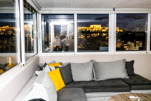 a living room with a couch in front of windows at PANORAMIC SUITE in Athens