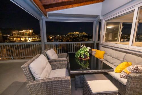 a balcony with wicker chairs and a glass table at PANORAMIC SUITE in Athens