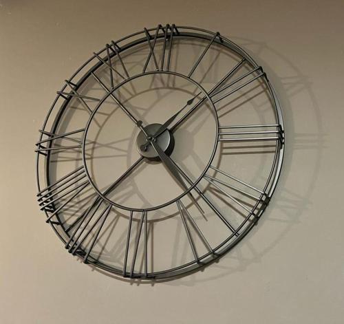 a large metal clock hanging on a wall at Residentie Pelikaan - nice view on the Leie in Deinze