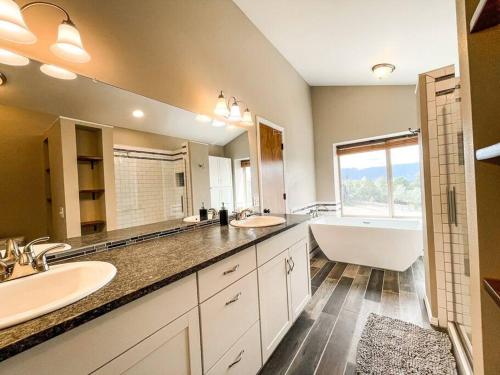 een badkamer met 2 wastafels, een bad en een bad bij Family Retreat near USAFA / Firepit/Games/Grill in Colorado Springs