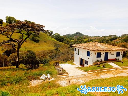 ein kleines weißes Haus auf einem Feld mit einem Hügel in der Unterkunft AZULEJO in Jericó