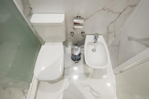 biała łazienka z toaletą i umywalką w obiekcie Spacious 2 Bedroom Villa Morra Apartment w mieście Asunción